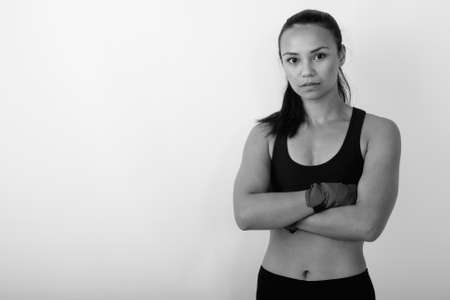 Studio shot of young Asian woman fighter with arms crossed against white backgroundの写真素材