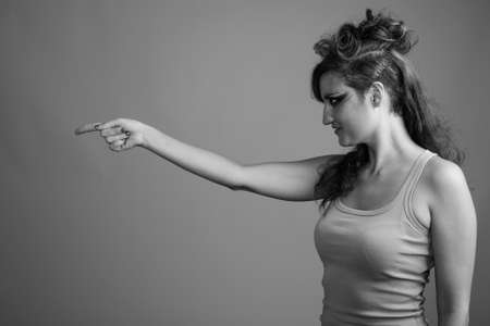 Beautiful woman with hair tied and makeup against gray backgroundの写真素材