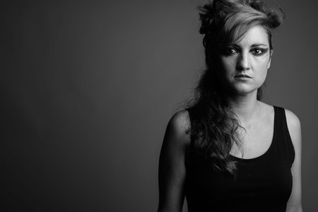 Beautiful woman with hair tied and makeup against gray background