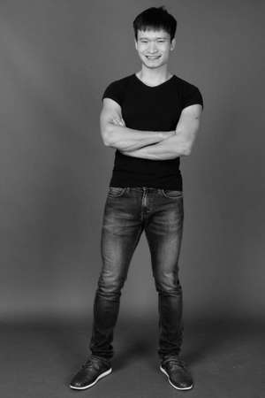 Studio shot of young Chinese man against gray backgroundの写真素材