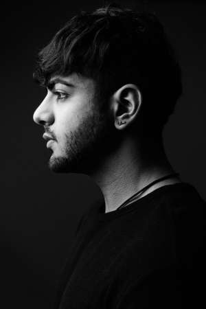 Young handsome bearded Indian man against gray backgroundの写真素材
