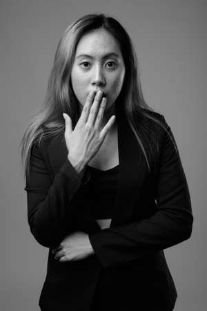 Portrait of young Asian businesswoman against gray backgroundの写真素材