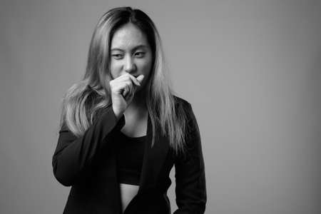 Portrait of young Asian businesswoman against gray backgroundの写真素材