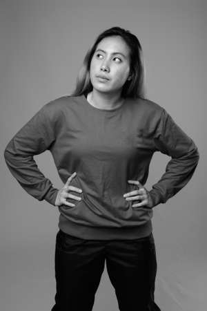 Portrait of young Asian woman against gray backgroundの写真素材