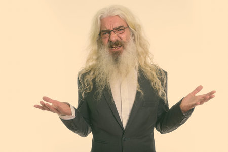 Studio shot of senior bearded businessman looking confused and angryの写真素材
