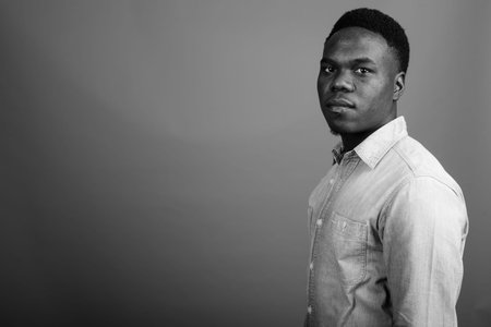 Young African man wearing denim shirt against gray background