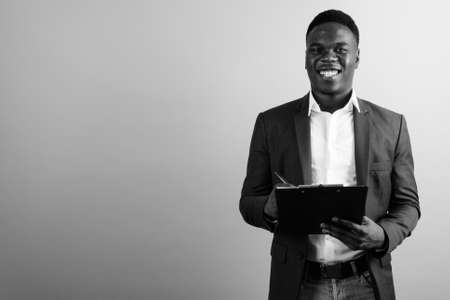 Happy young African businessman wearing suit against white backgroundの写真素材