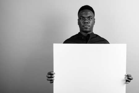 Young African businessman holding white board against white backgroundの写真素材