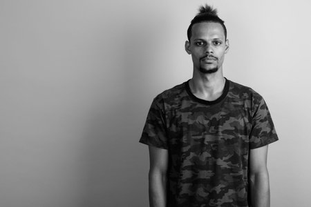 Young bearded handsome African man against gray background