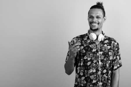 Happy young bearded handsome African man wearing headphonesの写真素材