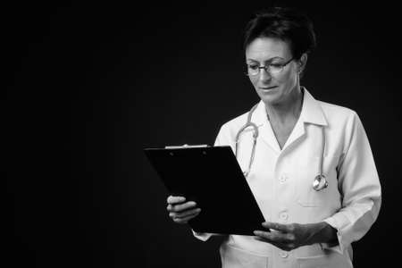 Mature beautiful woman doctor with short hair against black backgroundの写真素材