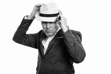 Studio shot of mature businessman fixing hat with both hands