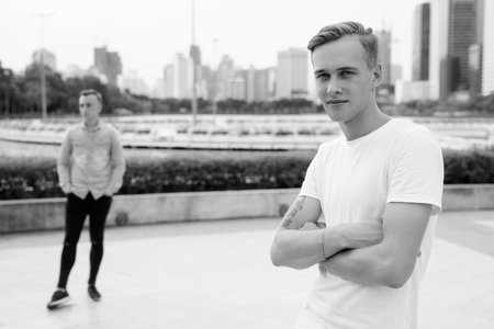 Two young handsome men with blond hair relaxing at the park together
