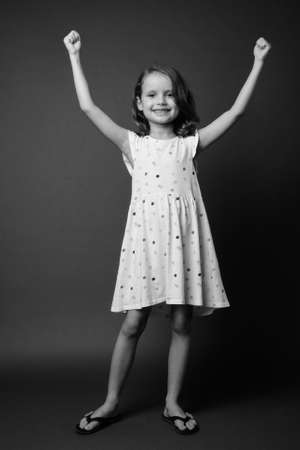 Cute young girl with blond hair against gray backgroundの写真素材