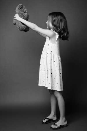 Cute young girl with blond hair against gray backgroundの写真素材