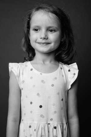 Cute young girl with blond hair against gray backgroundの写真素材