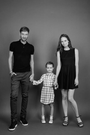 Young happy family bonding together against gray background
