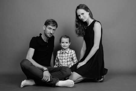 Young happy family bonding together against gray backgroundの写真素材