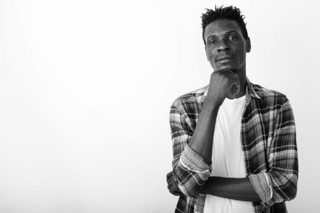 Studio shot of young black African man thinking against white background