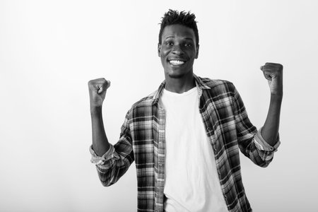 Studio shot of young happy black African man smiling while looking excited against white background