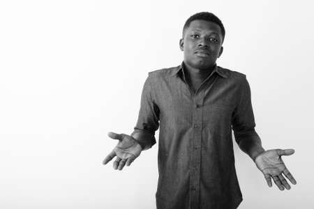Studio shot of young black African man looking confused against white backgroundの写真素材