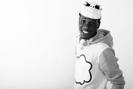 Studio shot of young happy black African man smiling while wearing white mask on top of head