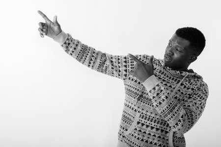 Studio shot of young black African man pointing both fingers up against white backgroundの写真素材