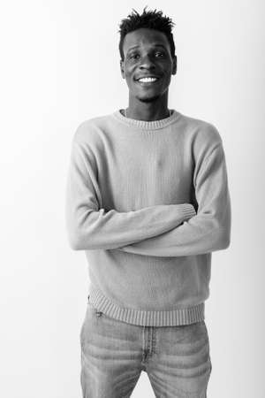 Studio shot of young happy black African man smiling and standing with arms crossedの写真素材
