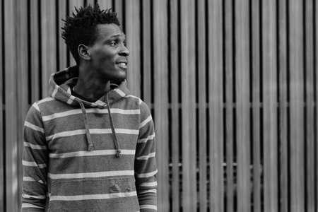 Profile view of young happy black African man smiling while thinking against wooden gate