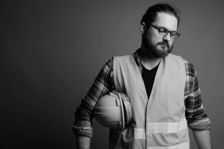 Young bearded man construction worker against gray backgroundの写真素材