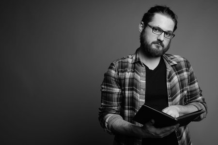 Young bearded man wearing checked shirt against gray background