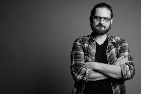 Young bearded man wearing checked shirt against gray background