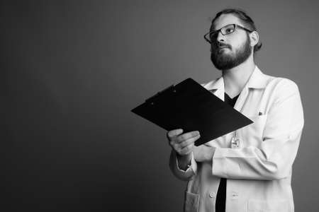 Young bearded man doctor against gray backgroundの写真素材