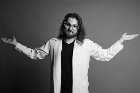 Young bearded man doctor against gray backgroundの写真素材