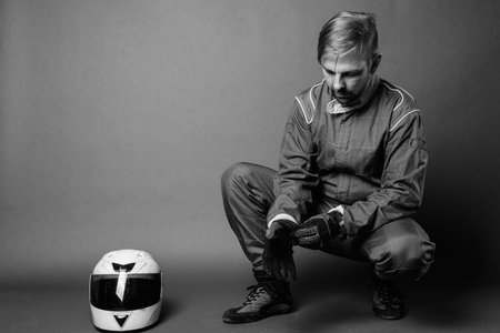 Blond bearded man motorcyclist with goatee in full gear against gray background