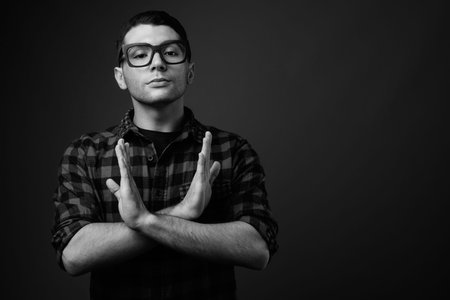 Portrait of young handsome hipster man against gray background