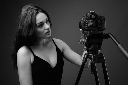 Studio shot of young beautiful woman against gray background