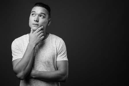 Young handsome multi ethnic man against gray background
