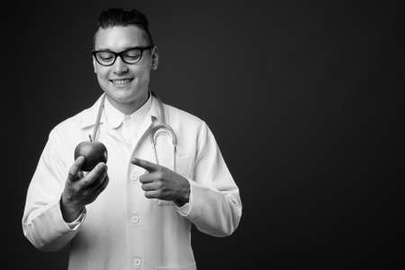 Young handsome multi ethnic man doctor against gray backgroundの写真素材