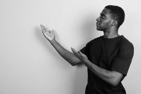 Young African man wearing black shirt against gray backgroundの写真素材