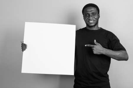 Young African man wearing black shirt against gray backgroundの写真素材