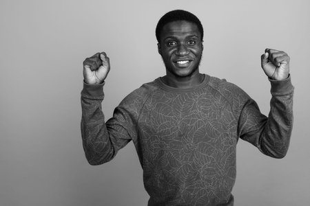 Young African man wearing long sleeved shirt against gray background