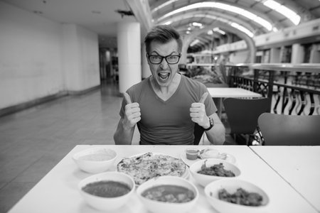 Young handsome tourist man enjoying Indian cuisine at the restaurantの写真素材