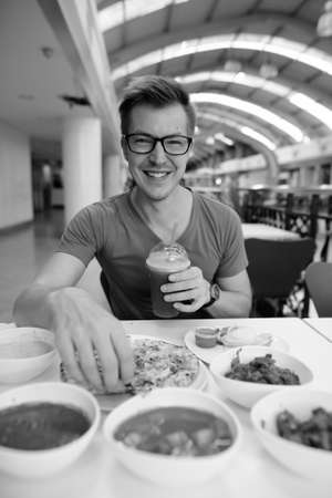 Young handsome tourist man enjoying Indian cuisine at the restaurantの写真素材
