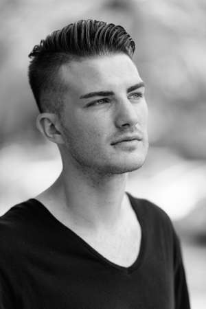 Face of young handsome man thinking while looking at distance in the parking lotの写真素材