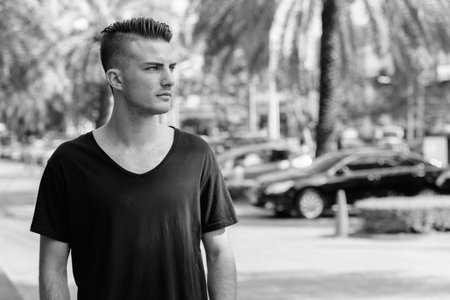 Young handsome man standing while thinking in the parking lot