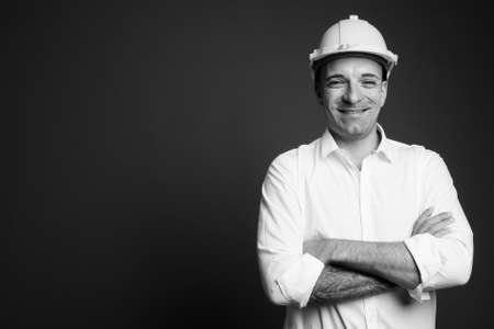 Businessman wearing hardhat against gray backgroundの写真素材
