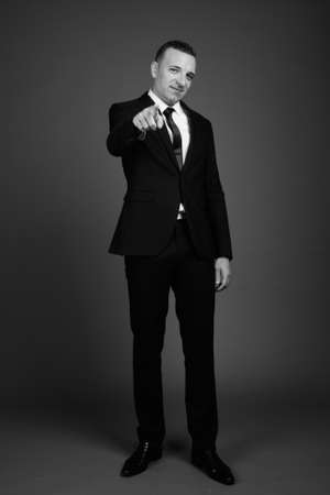 Businessman wearing suit against gray backgroundの写真素材