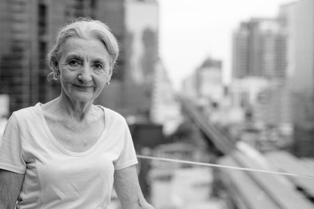 Beautiful senior woman with blond hair against view of the city
