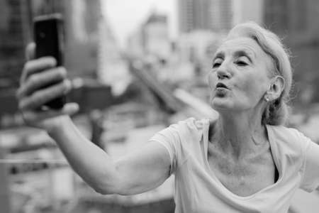 Beautiful senior woman with blond hair against view of the cityの写真素材
